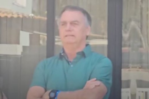 Jair Bolsonaro sorri e acena na varanda de casa em Brasília